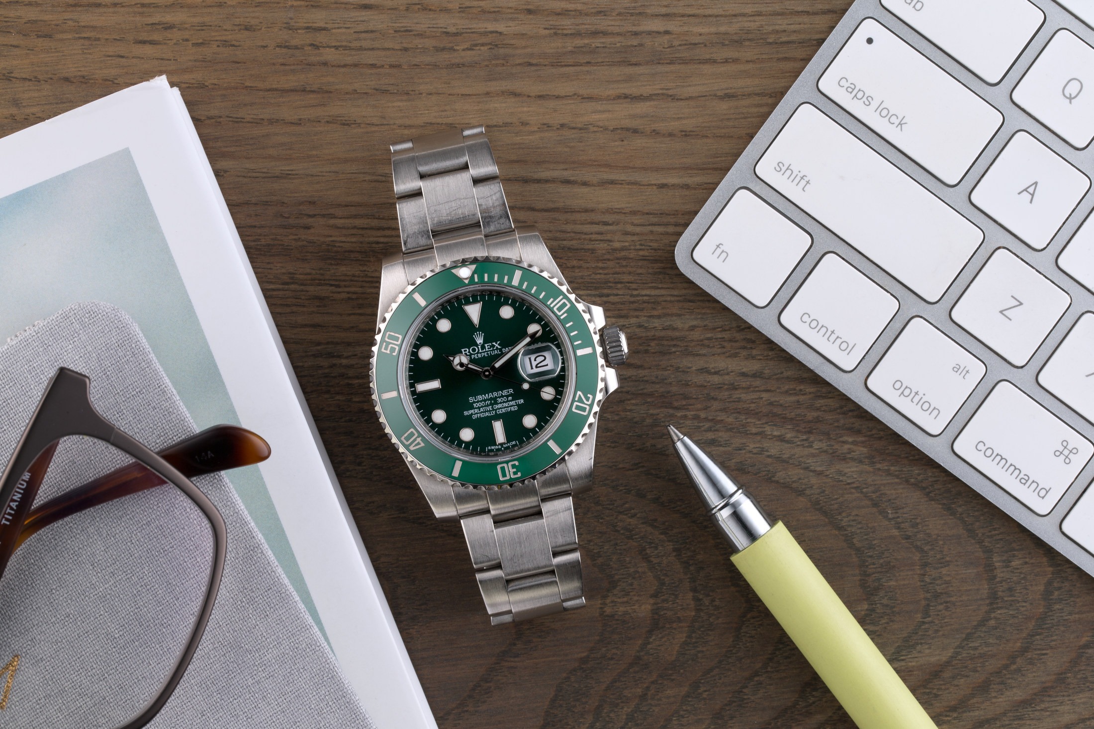 Styled Product Photo of vintage metal Rolex watch. Watch sitting on wood desk with computer and tablet.