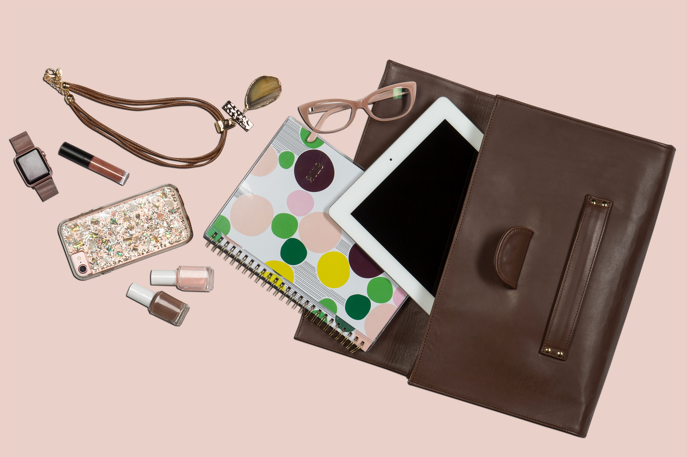 Flat lay photography for Bagwell handbag collection. Brown leather Clutch on table with contents spilling out.