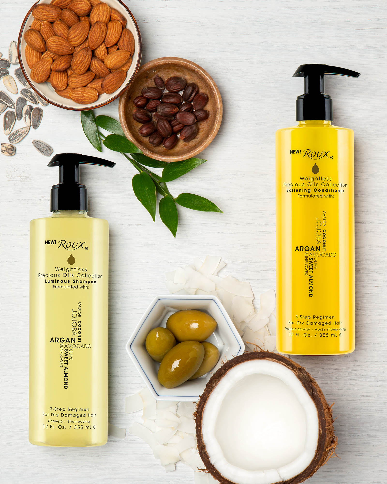 Bottles of Roux shampoo and conditioner surrounded by natural ingredients found in product: Almonds, coconut, sunflower seed, olive oil